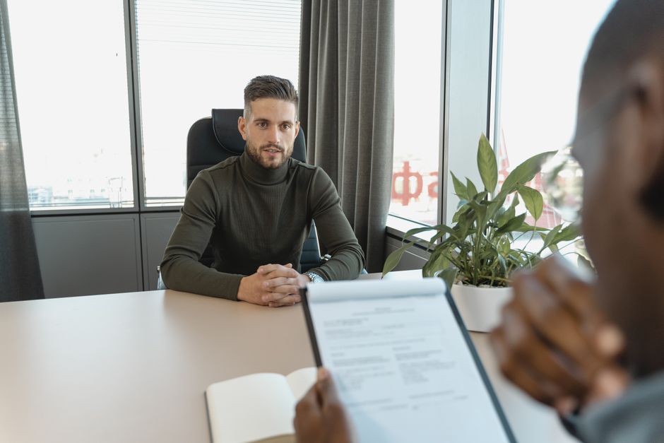 Two people talking across a table in a bright office