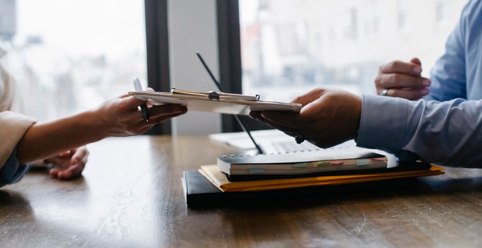 Person typing a resume on a laptop with a notebook and coffee nearby